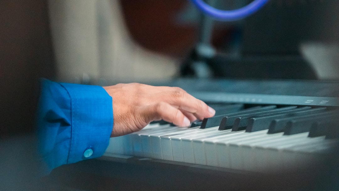 A person's hand on a keyboard in front of a microphone