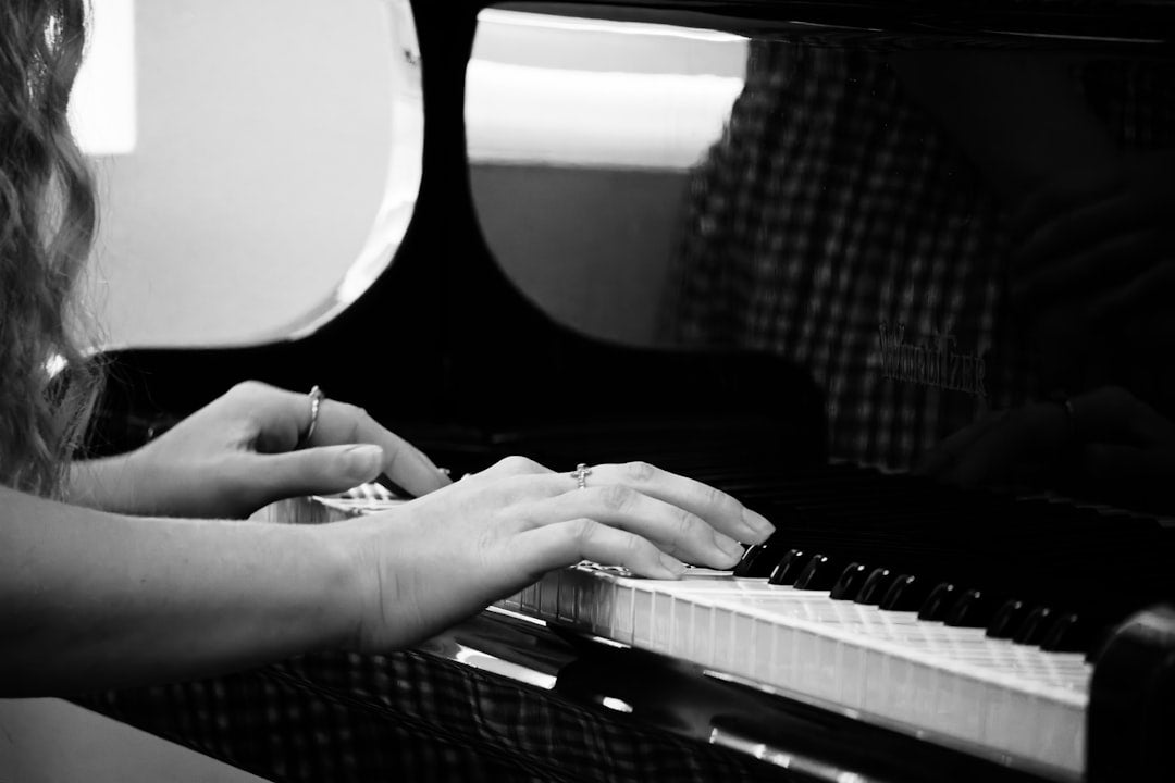 Hands playing a grand piano in black and white
