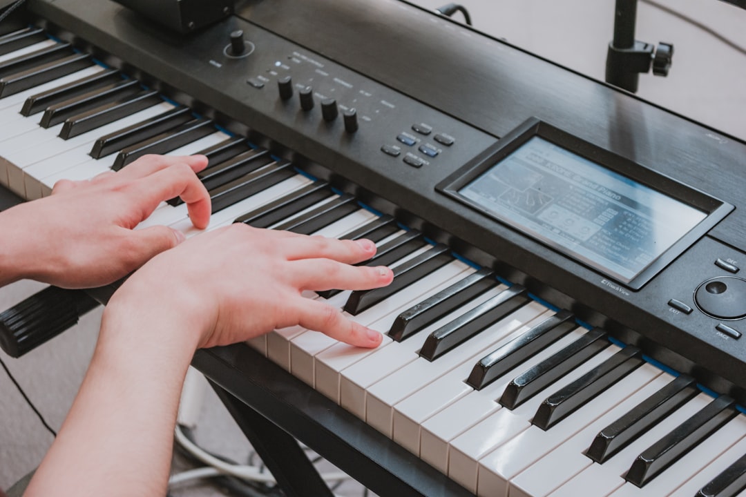 Hands playing a digital piano keyboard with a screen